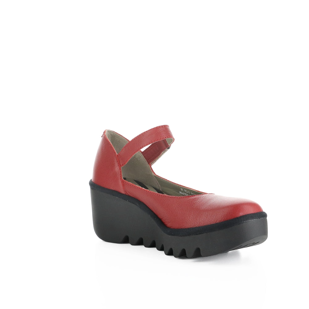 A red Mary Jane style platform wedge shoe with a black lug sole, shown from a three-quarters angle on a white background.