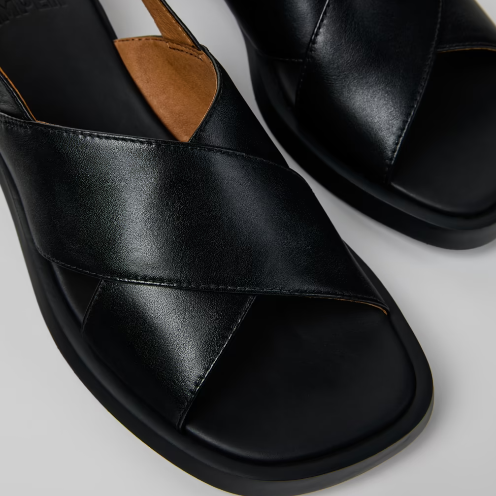 Black leather sandals with open-toe design on a light gray background