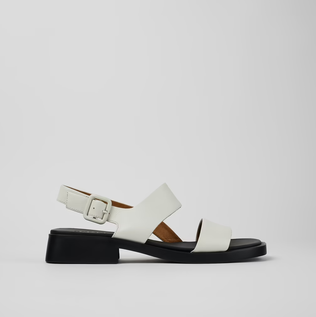 White sandal with a black block heel on a light gray background