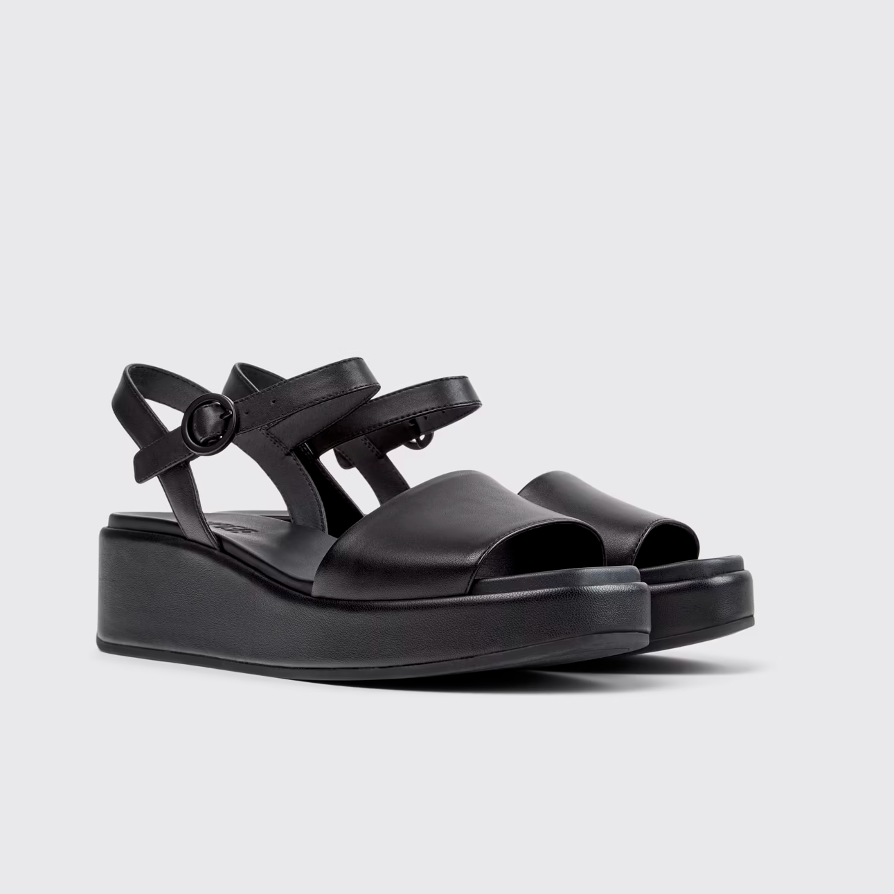 Black sandals with multiple straps on a light gray background