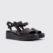 Black sandals with multiple straps on a light gray background
