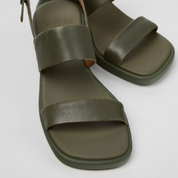 Pair of green sandals with brown straps on a light gray background