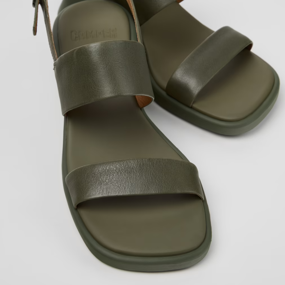 Pair of green sandals with brown straps on a light gray background
