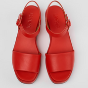 Red sandals with a brand logo on a light gray background