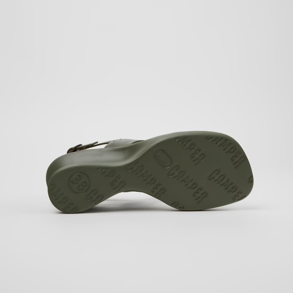 Green sandal with brand name on sole against a white background