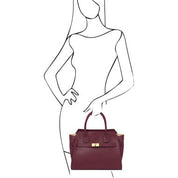 Burgundy handbag held by a stylized woman on a white background