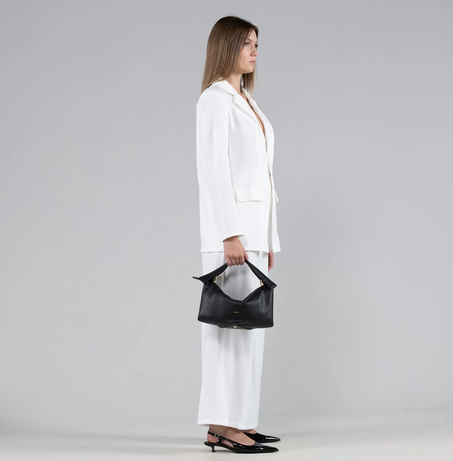 Woman holding a black handbag against a gray background