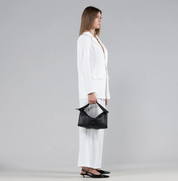 Woman holding a black handbag against a gray background